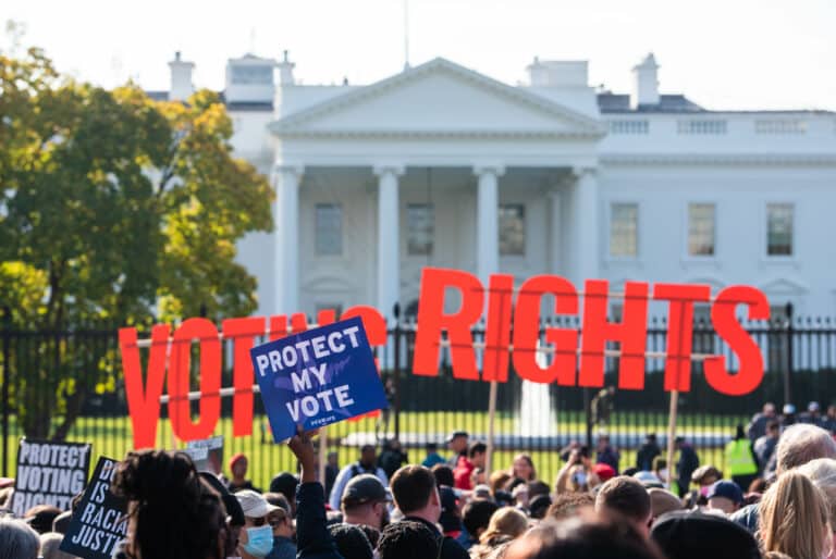 Voting Rights protestors with red signs that say Voting Rights and a blue sign that says Protect My Vote