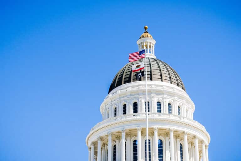 California state capitol building with flags waving in front